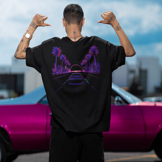 Model wearing the black GTA Neon Horizon Drive Tee inspired by Grand Theft Auto VI outdoors featuring a colorful neon graphic design