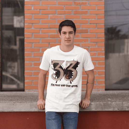 Person wearing a white t-shirt with a design and text, standing against a brick wall.