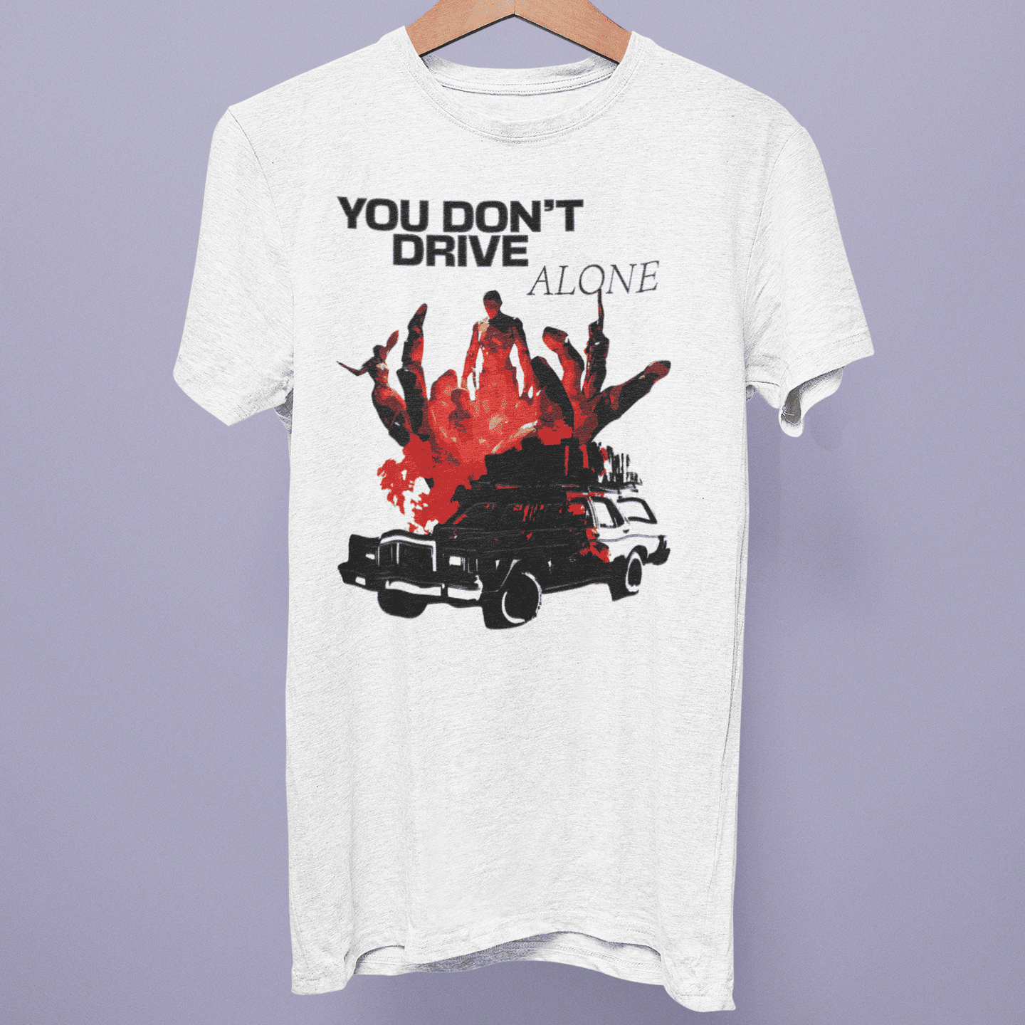 Front view of the Pacific Drive Collection T-shirt on a hanger, showing “You Don’t Drive Alone” car artwork on white fabric.