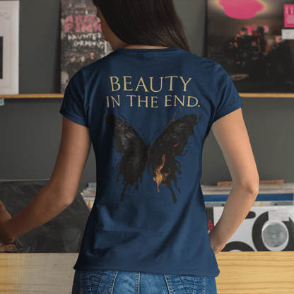 Person wearing a blue t-shirt with a butterfly design and 'BEAUTY IN THE END.' text in a room with records and photos.