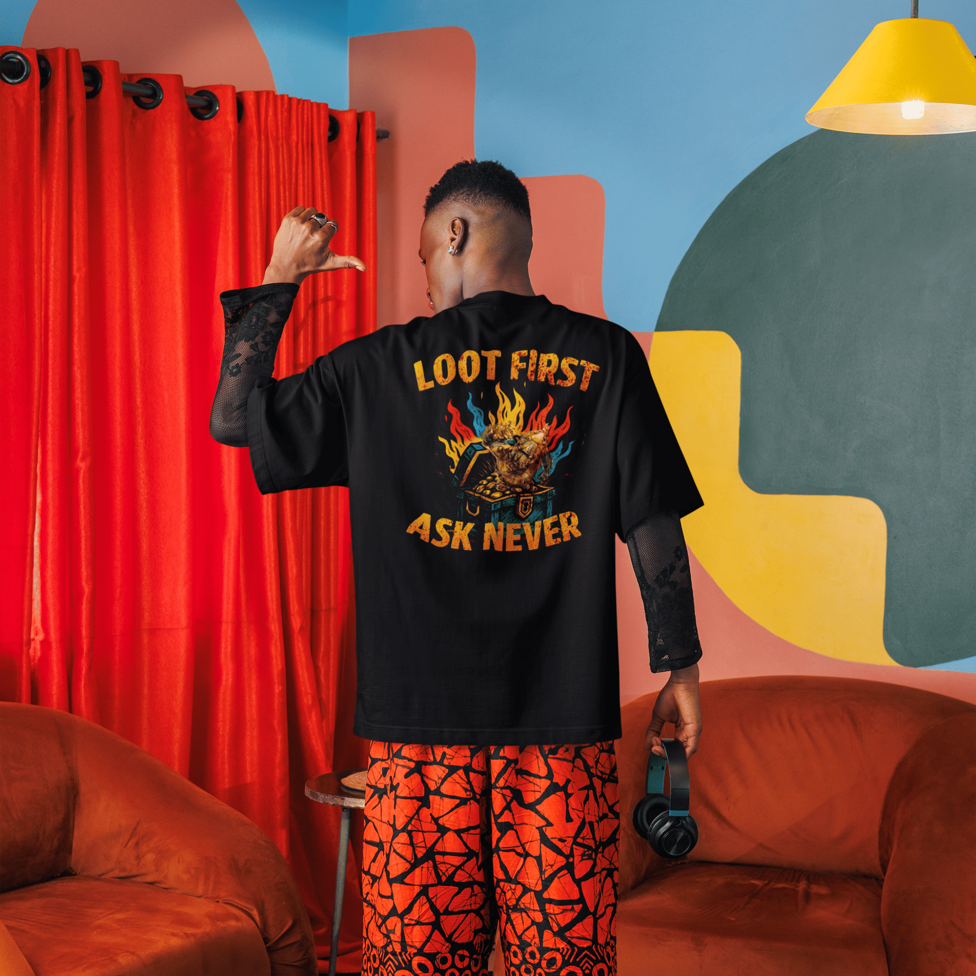 Person wearing a black t-shirt with colorful text and orange pants in a vibrant room.