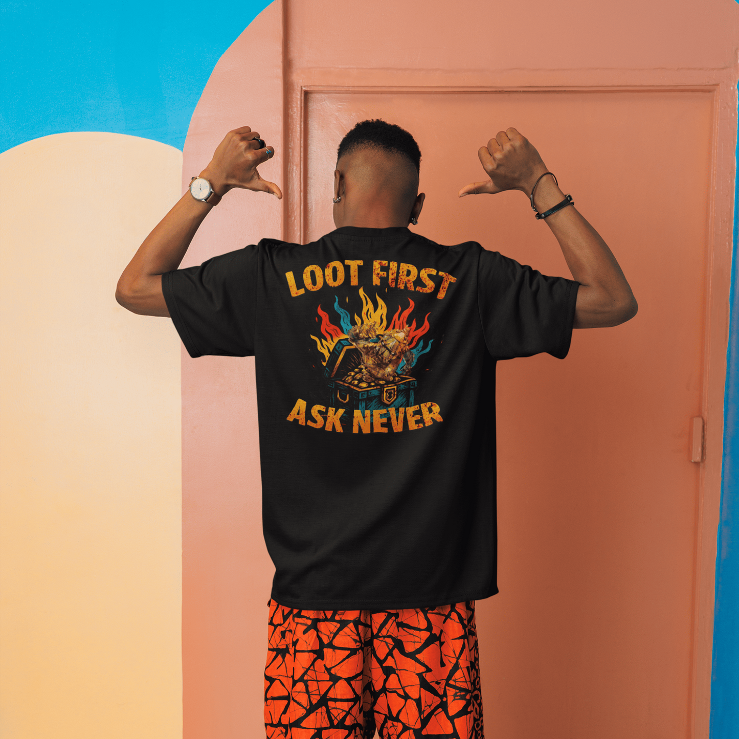 Person wearing a black t-shirt with text and colorful pants in front of a colorful wall.