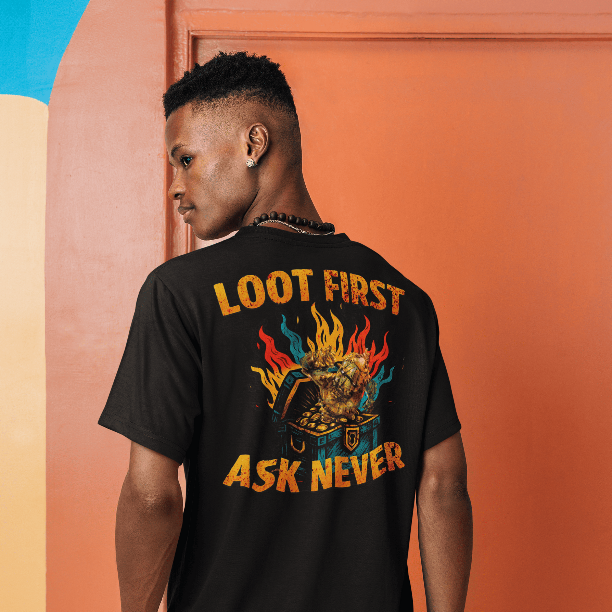 Person wearing a black t-shirt with colorful text and graphics, standing against an orange wall.