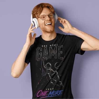 Male gamer reacting playfully in One More Game T-shirt, a late-night gaming graphic tee on purple background.