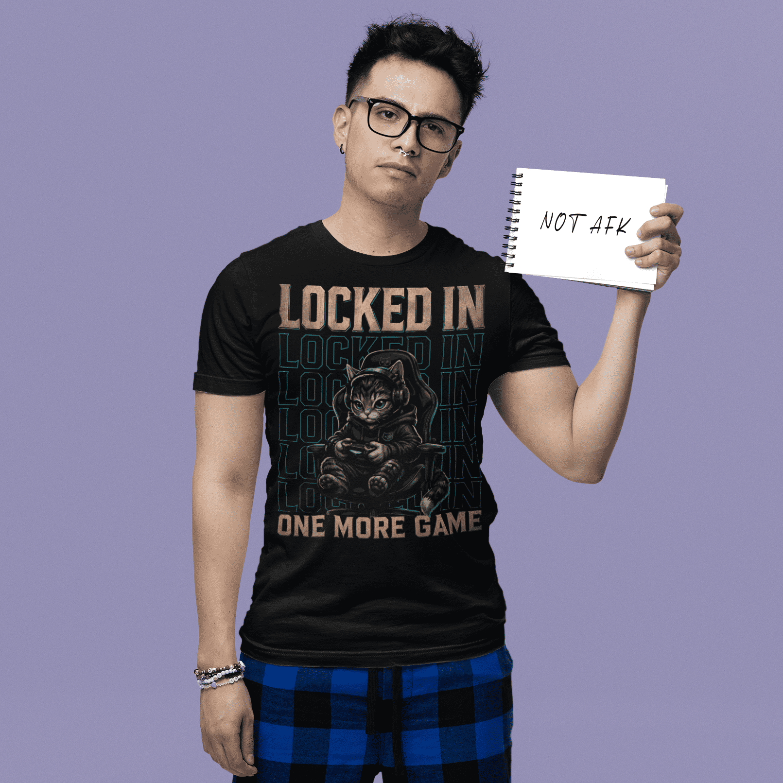 Male gamer holding a sign in Locked In Cat Gamer T-Shirt with one more game artwork on a purple studio background.