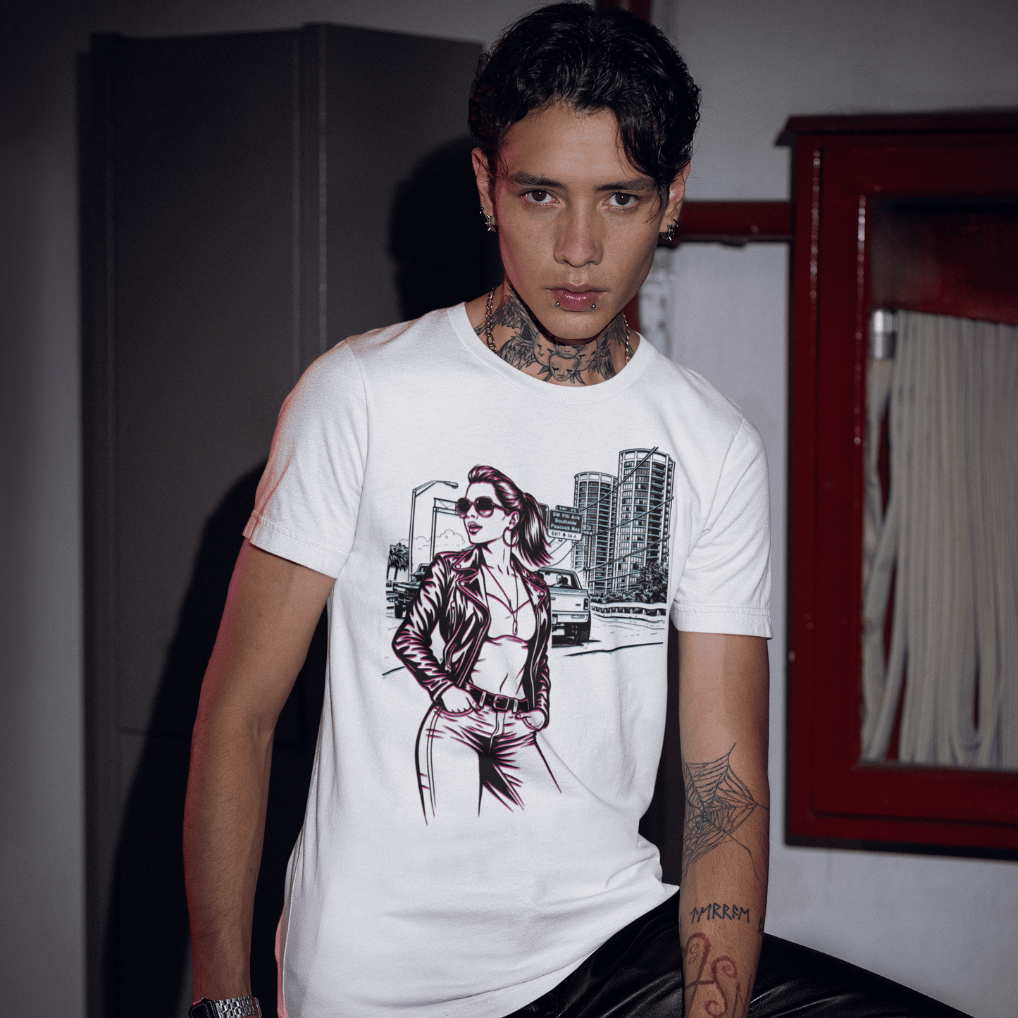 Person wearing a white t-shirt with a graphic design, sitting indoors.