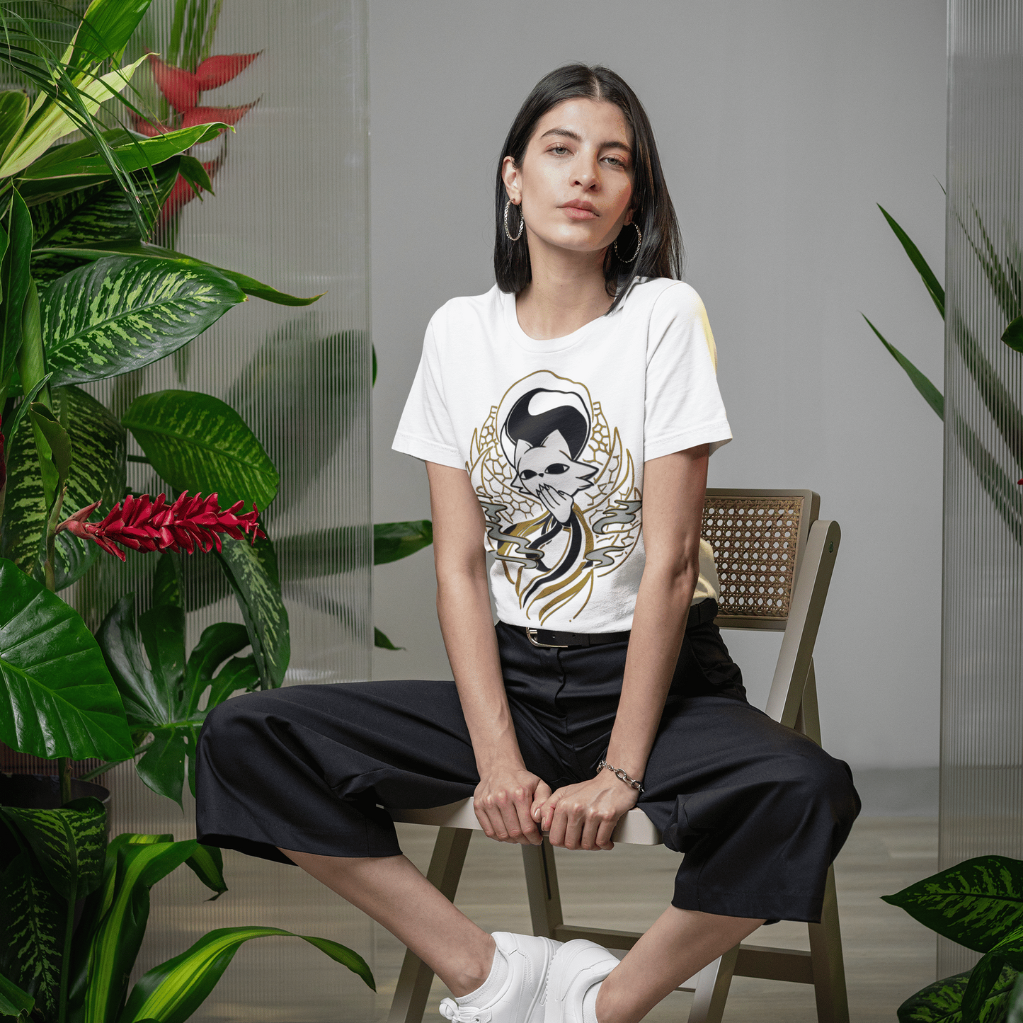 Female model seated indoors wearing the white Nine Sols Yin Yang Tee – Balance Presence in a botanical lifestyle setting.