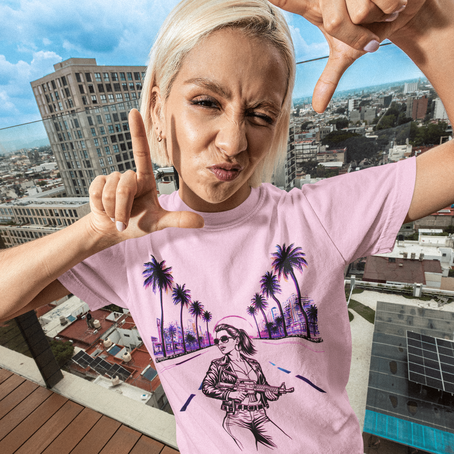 Person wearing a pink t-shirt with a graphic design, making hand gestures on a rooftop with cityscape background