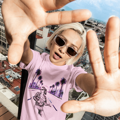 Person wearing a pink t-shirt with a graphic design, standing on a rooftop with a cityscape background.