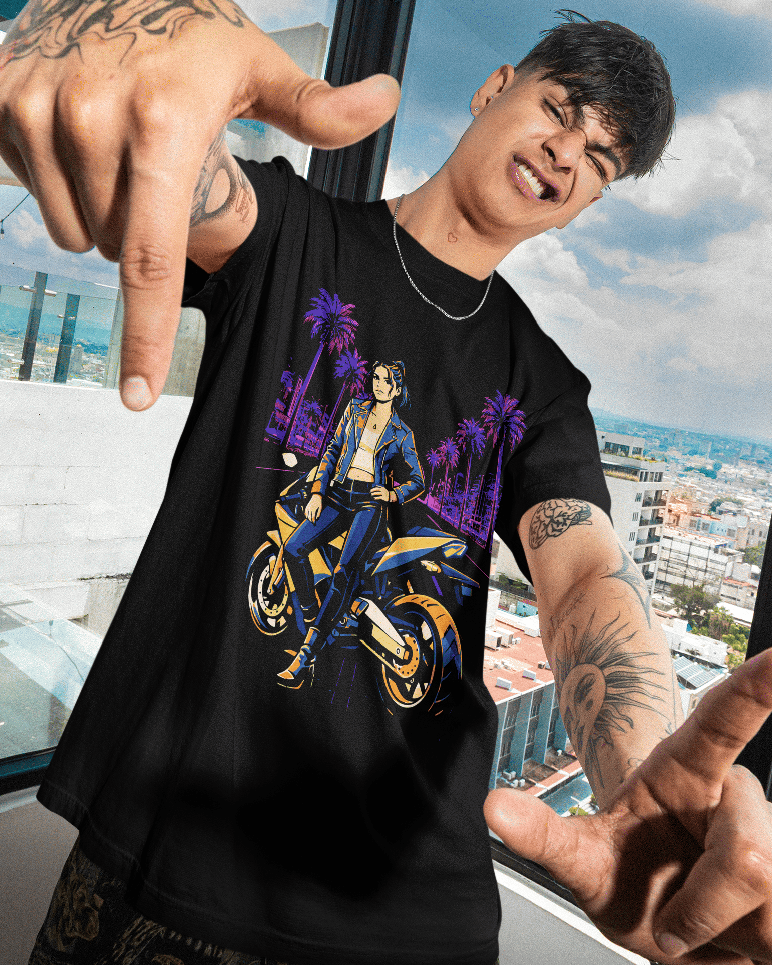 Person wearing a black t-shirt with a graphic design, standing in front of a large window with a cityscape view.