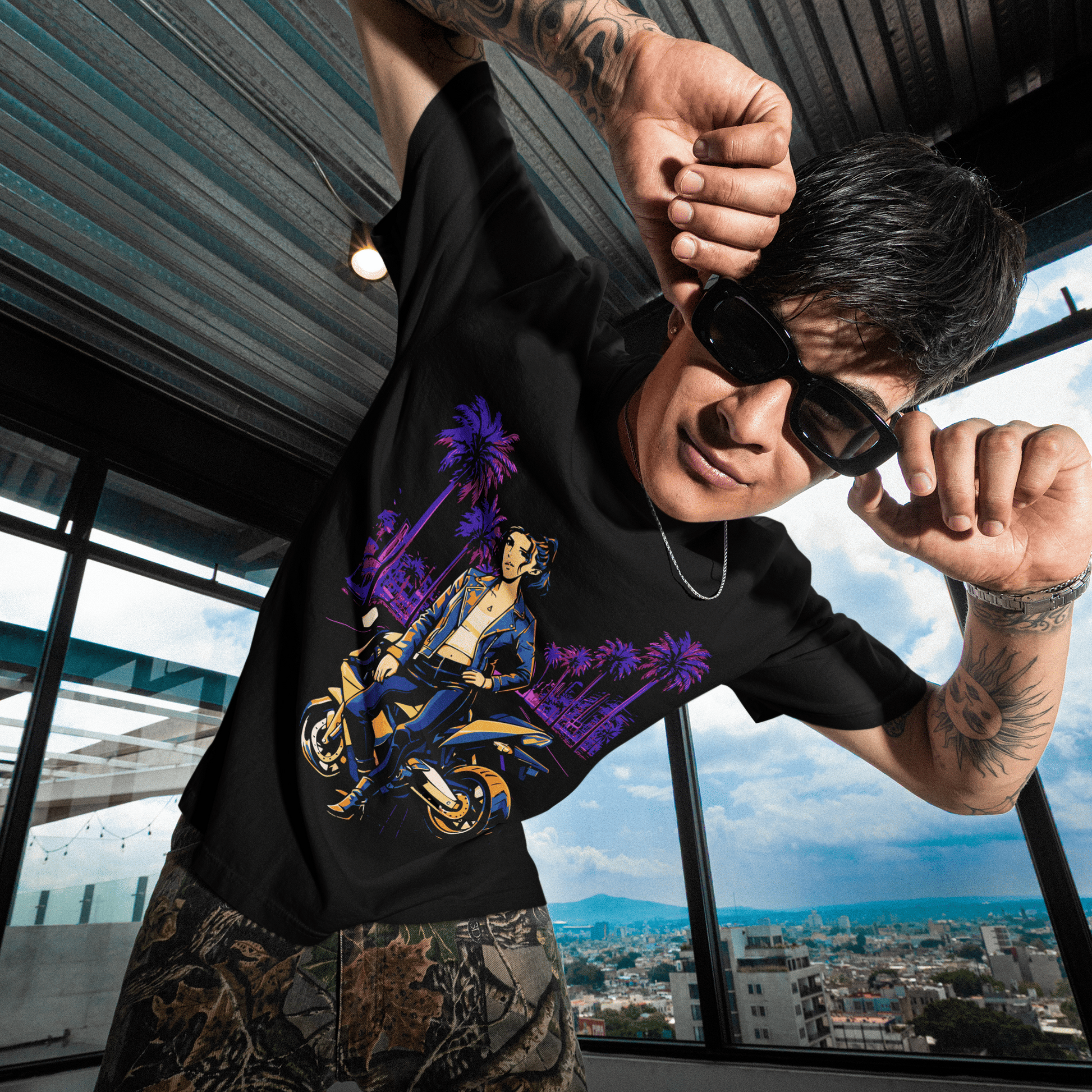 Person wearing a black t-shirt with a graphic design, standing in a room with large windows showing a cityscape.