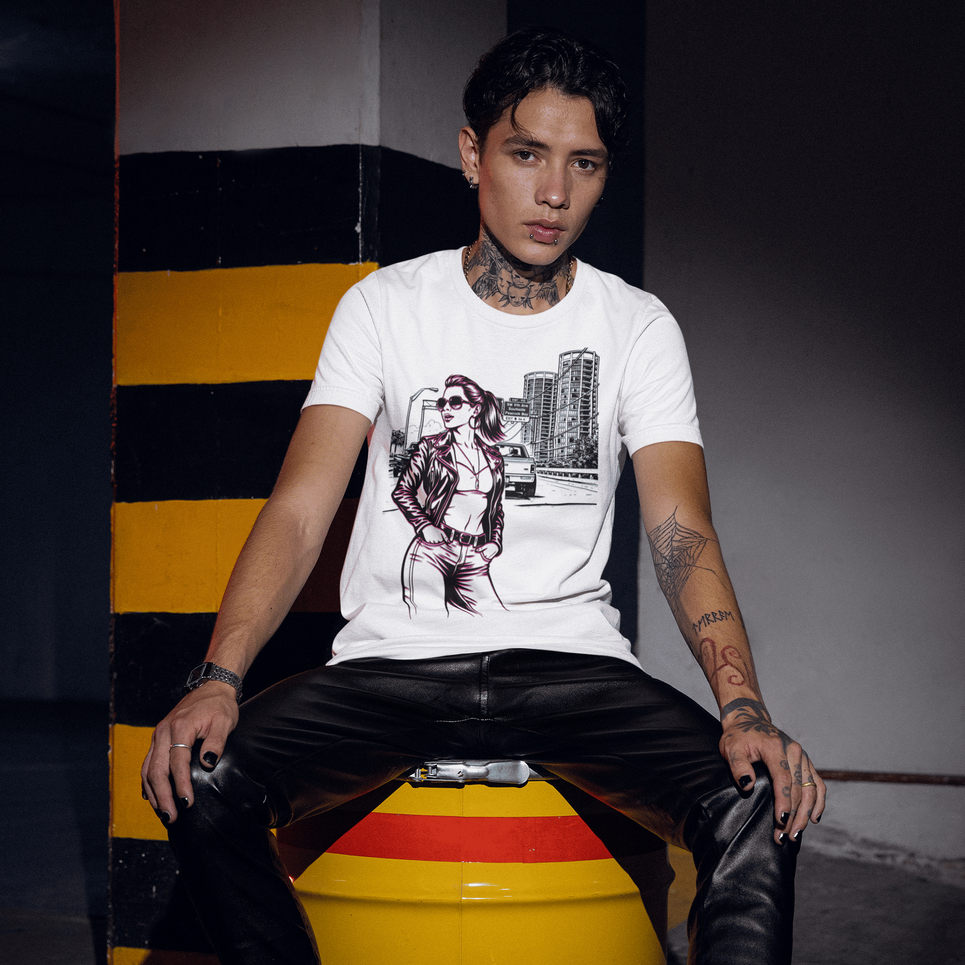 Person sitting on a yellow barrel with black and red stripes, wearing a white t-shirt with a graphic design.