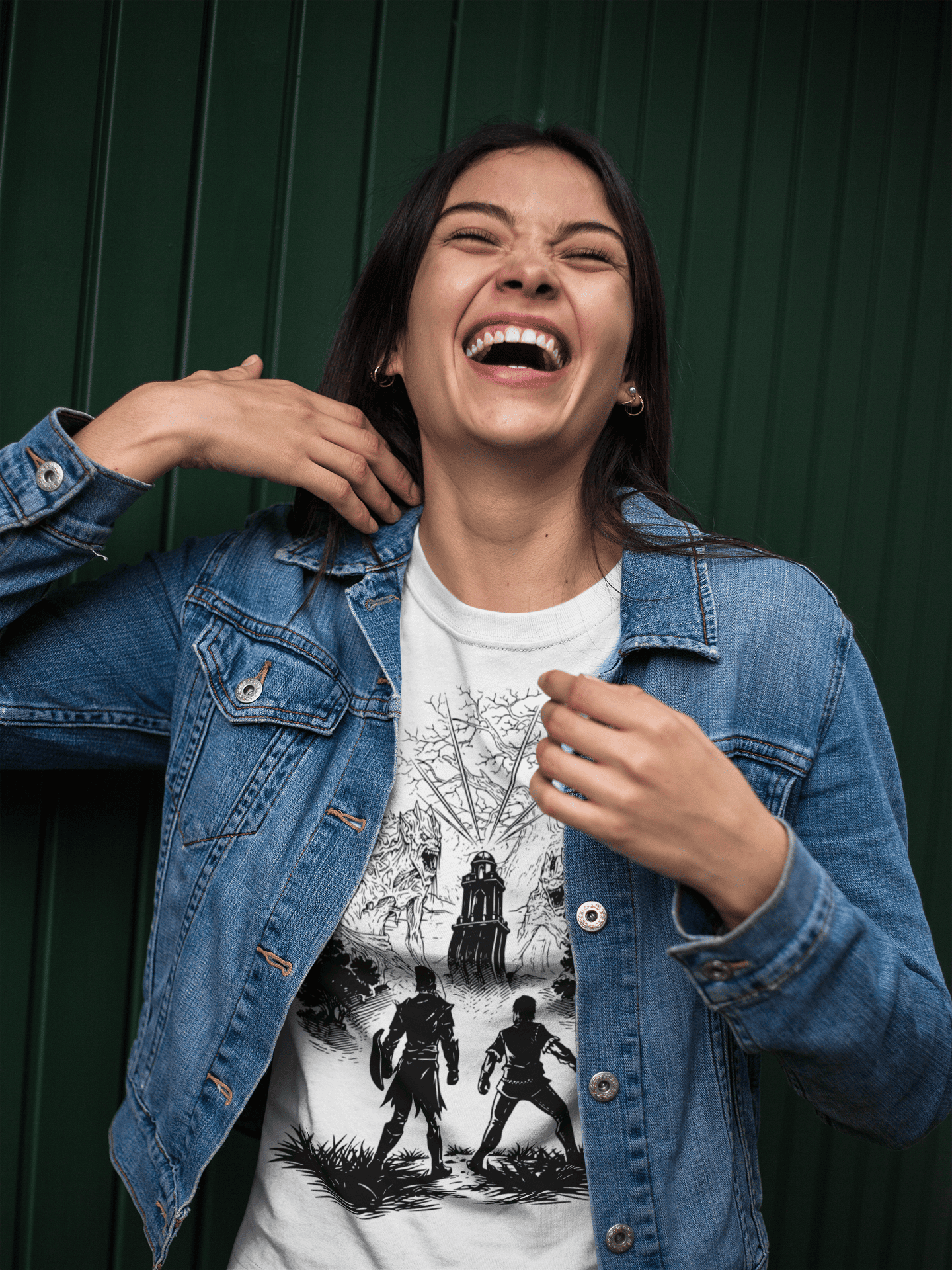 Person wearing a denim jacket and graphic t-shirt with a dark background