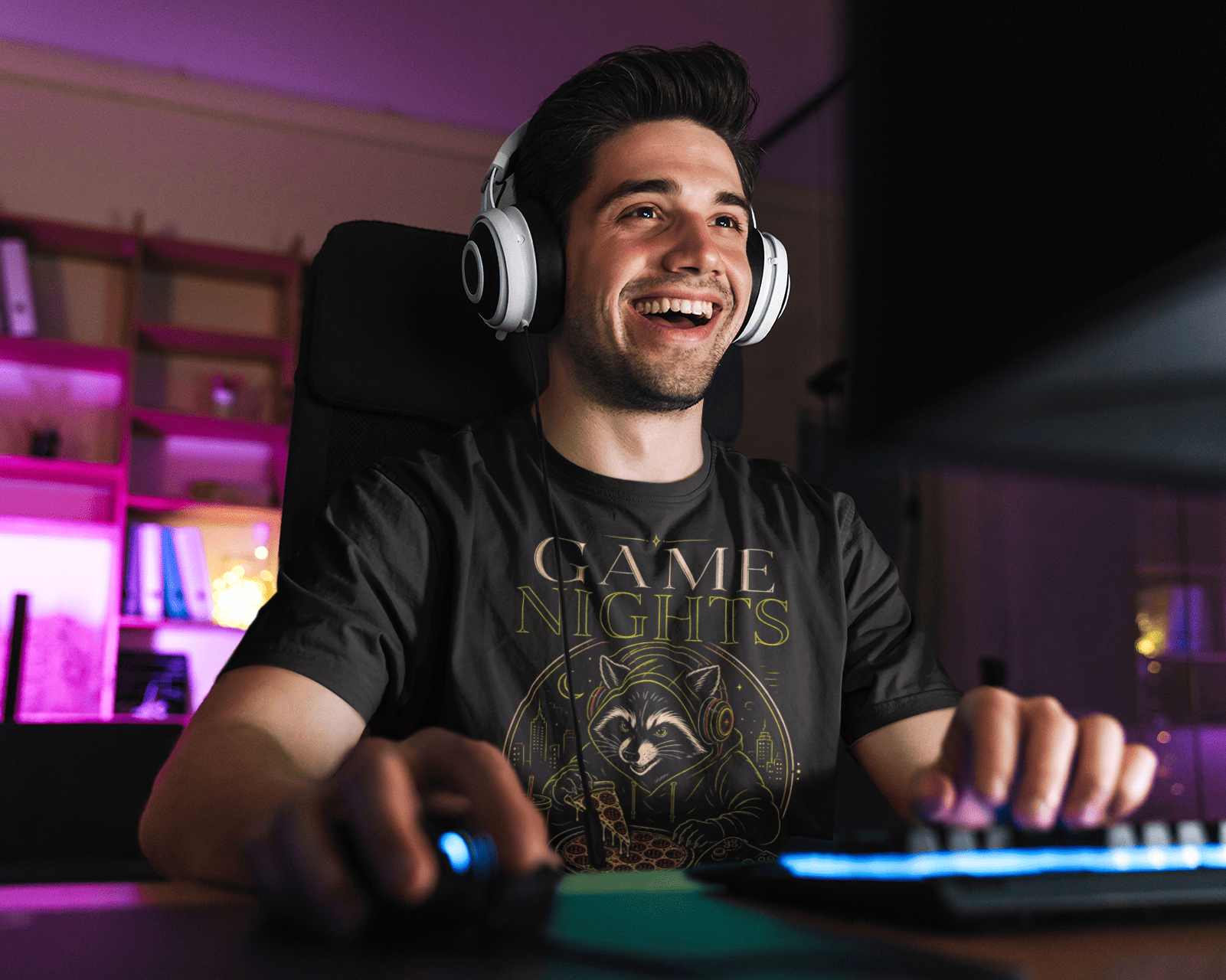 Man wearing headphones and a 'Game Nights' t-shirt in a gaming setup with colorful lighting.