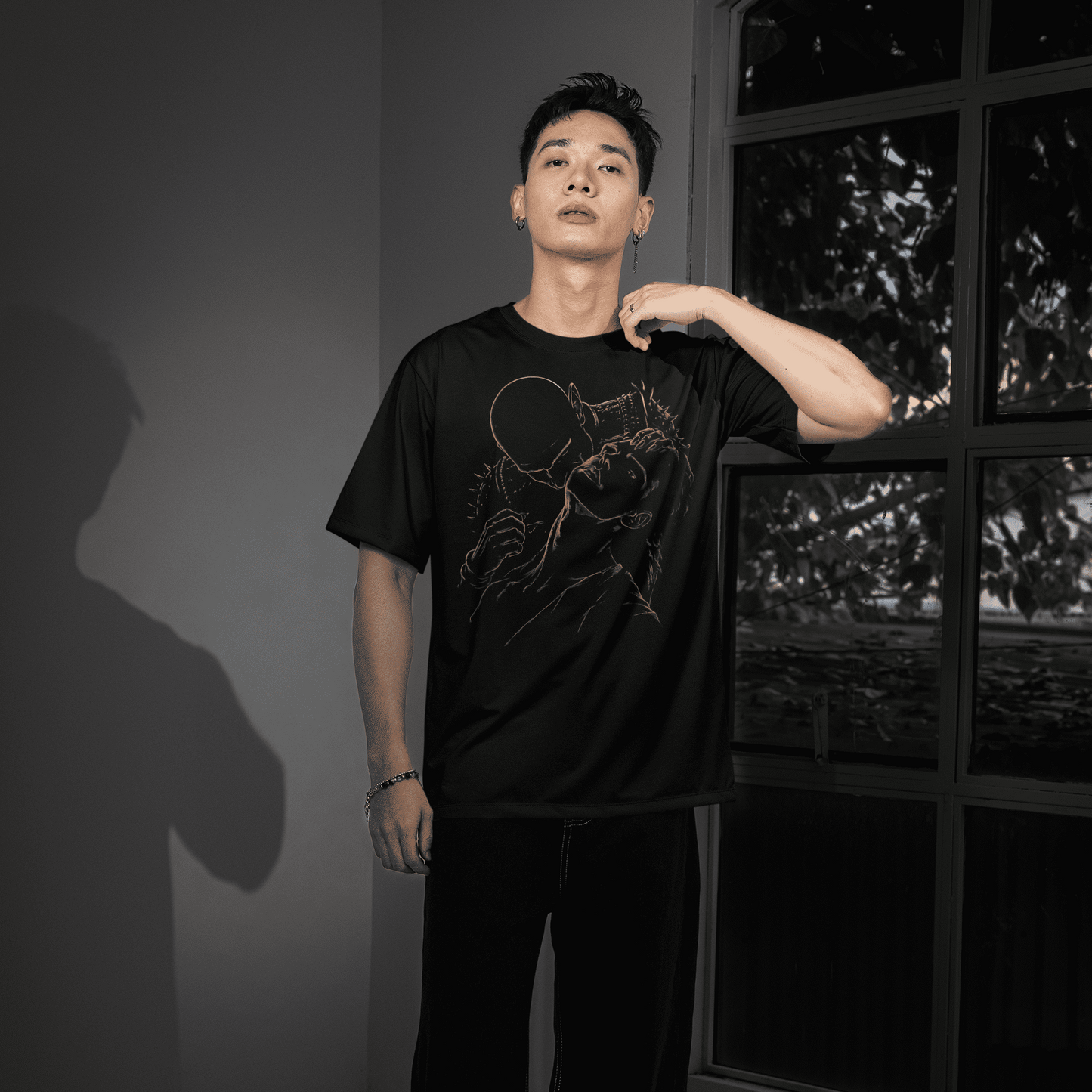 Front standing model view of The Blood of Dawnwalker Sire Embrace T-Shirt with subtle gold vampire artwork on a black tee.