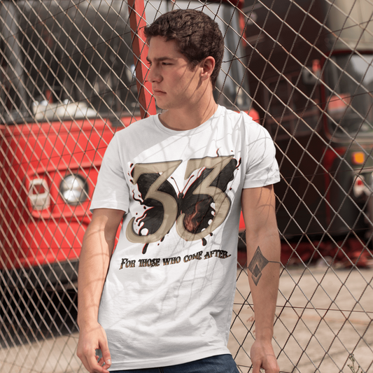 Man wearing a white t-shirt with a graphic design standing in front of a red vehicle.