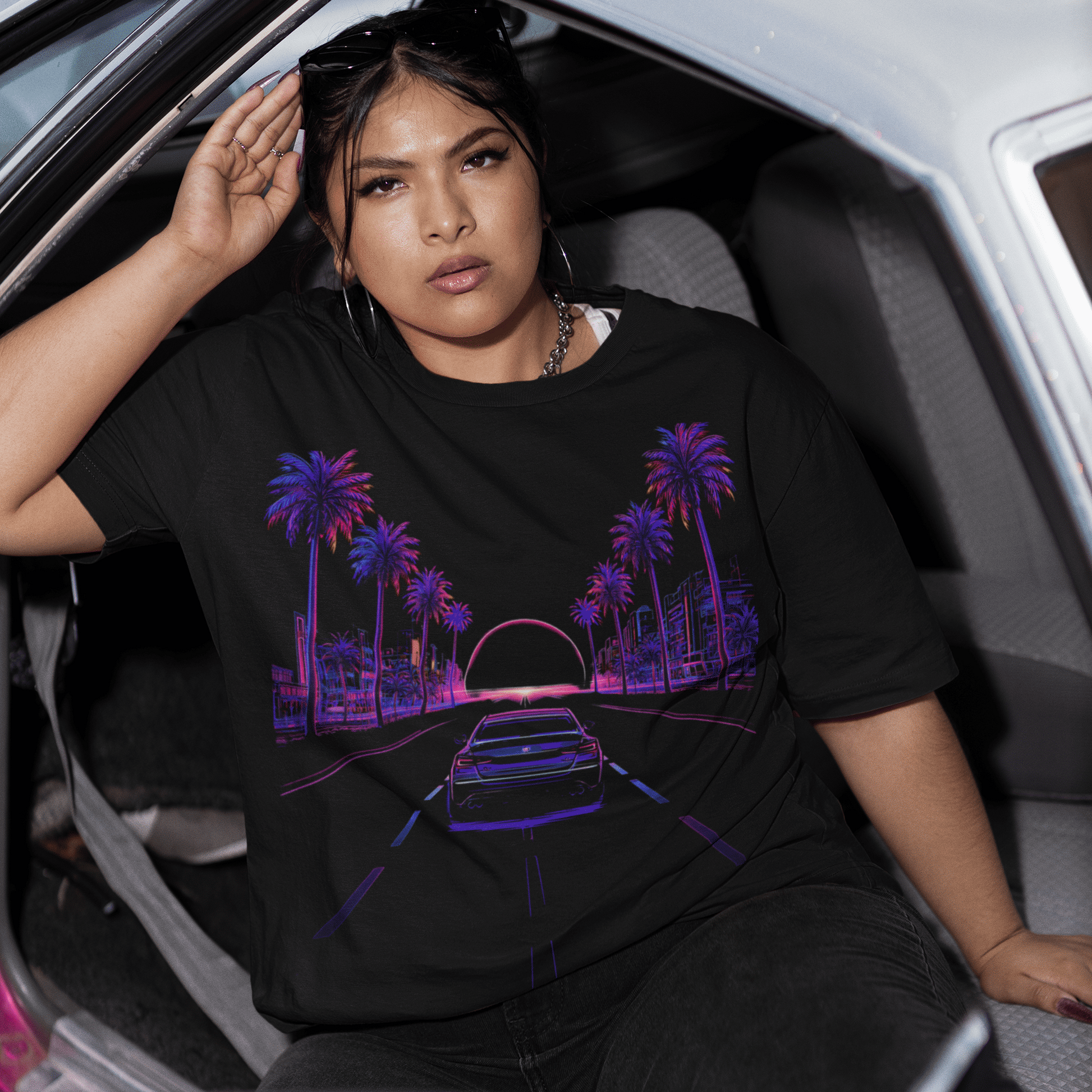 Woman sitting in a car wearing a black t-shirt with a colorful graphic design.