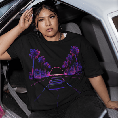 Woman sitting in a car wearing a black t-shirt with a colorful graphic design.