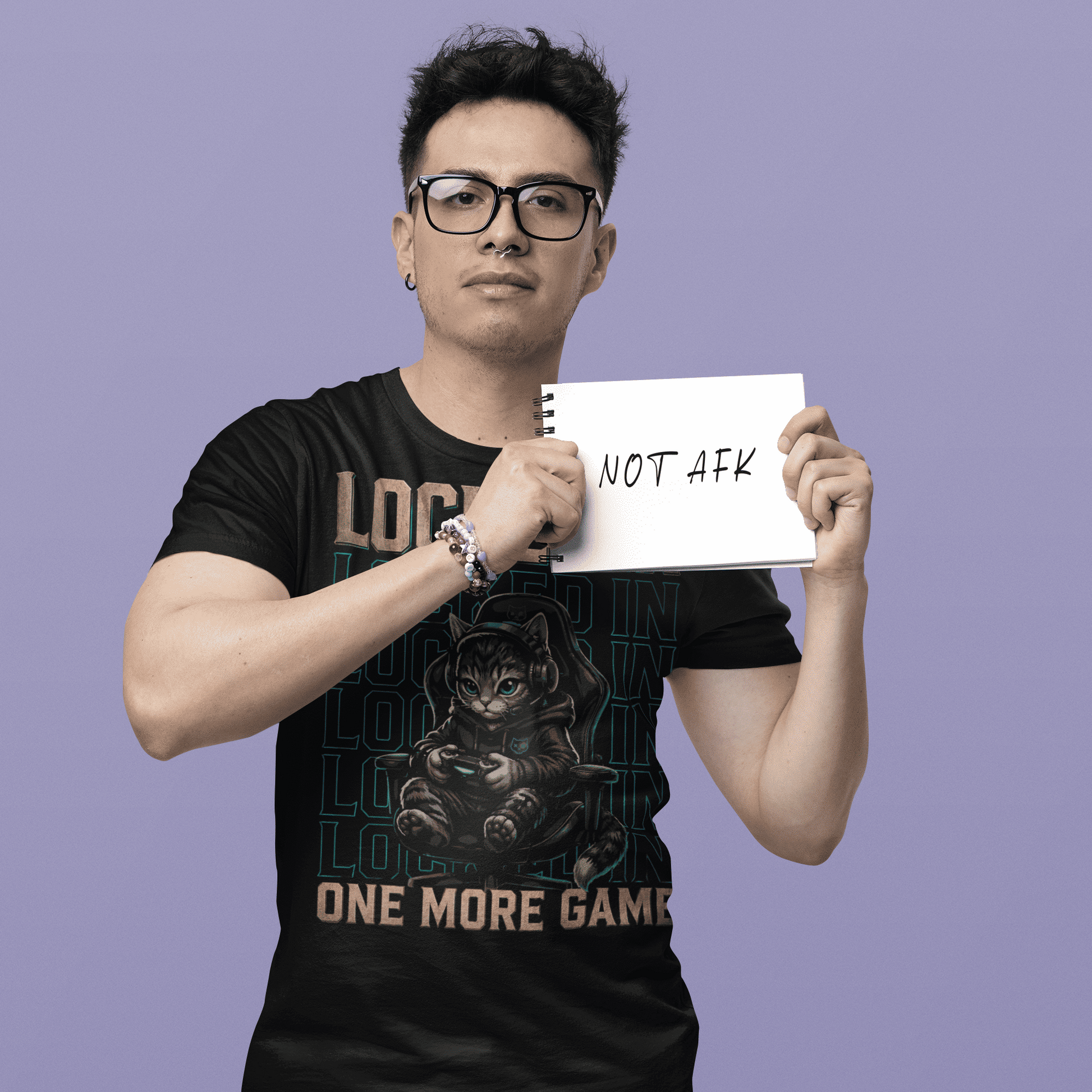 Male gamer holding a gaming note in Locked In Cat Gamer T-Shirt featuring dark cat gamer artwork.