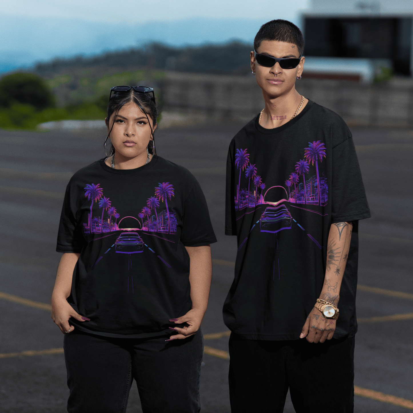 Two people wearing black t-shirts with purple graphics in a parking lot.