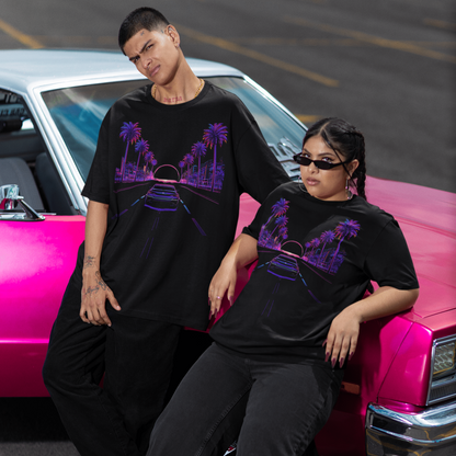 Two people wearing matching black outfits with purple designs sitting on a pink car.