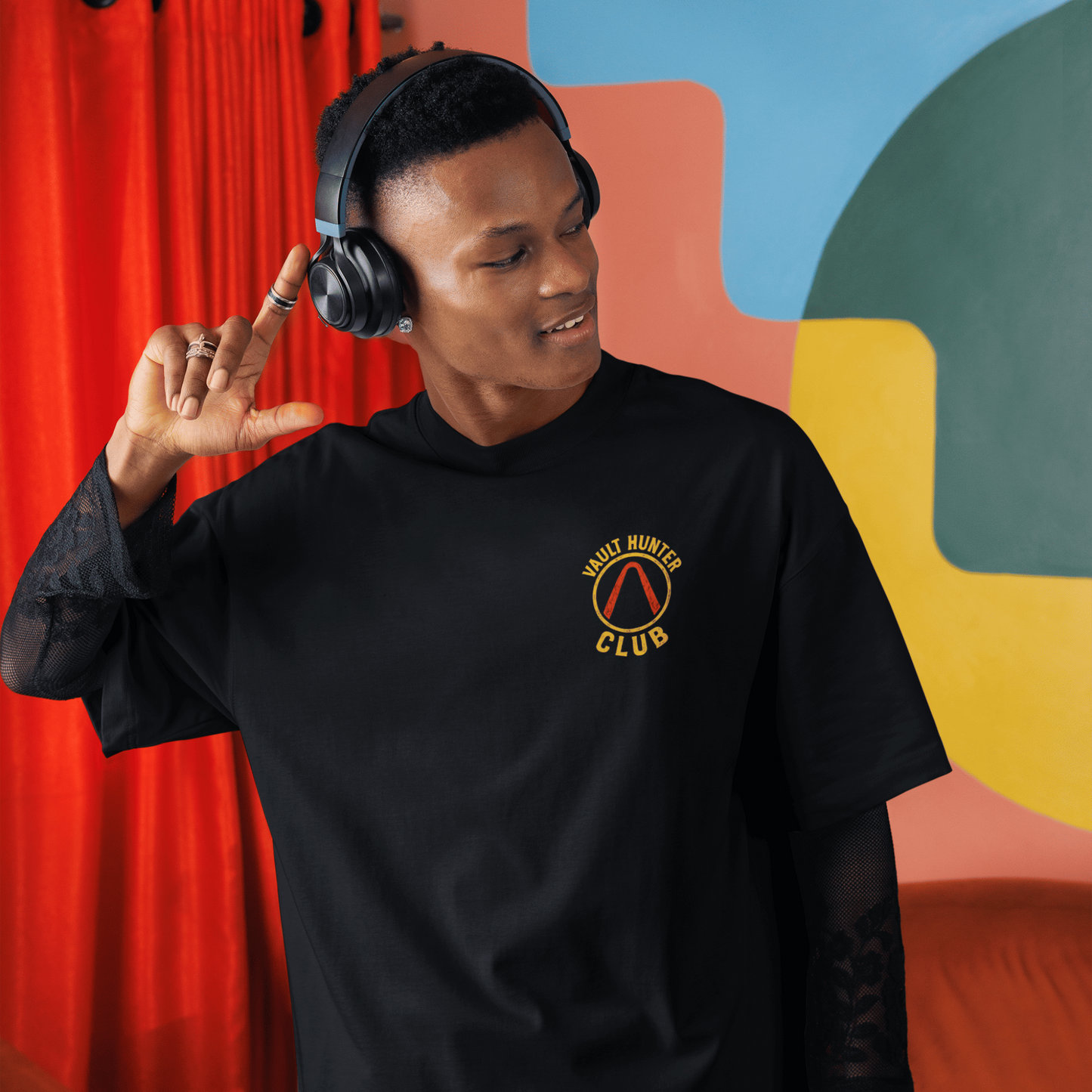 Person wearing a black sweatshirt with a logo in a colorful room