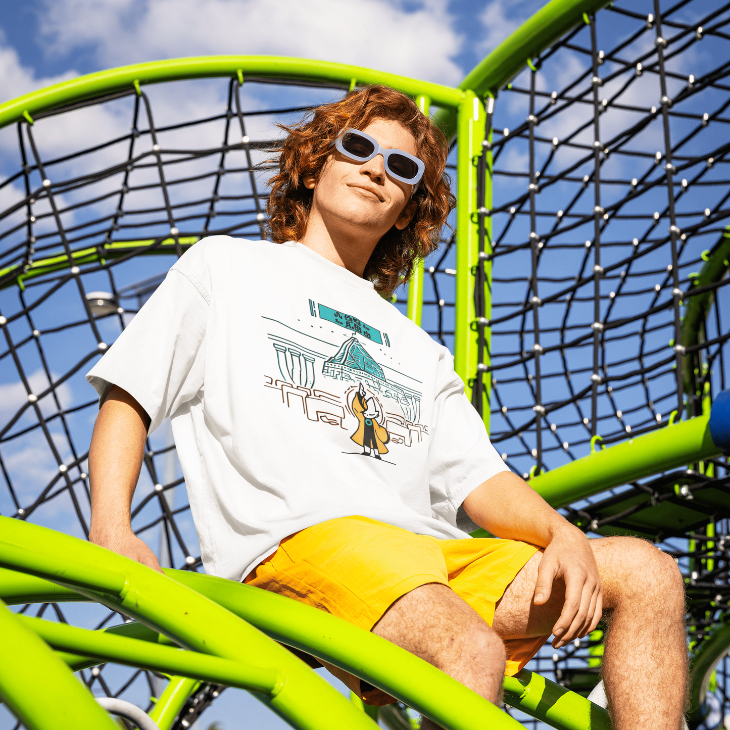 Male model wearing the white Nine Sols Taopunk Tee – Shrine Presence on a bright green playground structure.