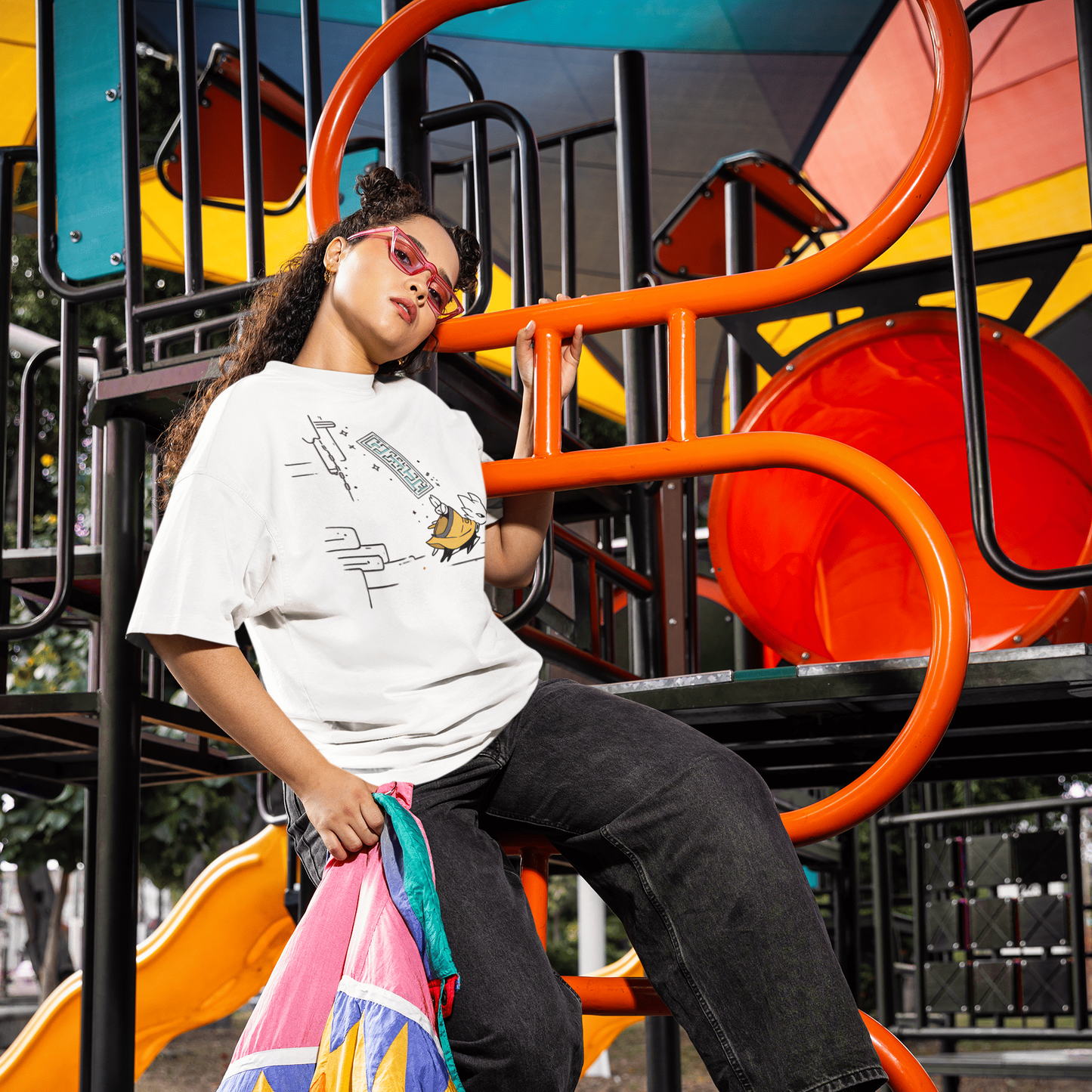 Male model wearing the white Nine Sols Action Tee – Seal Motion while leaning on a colorful playground structure.