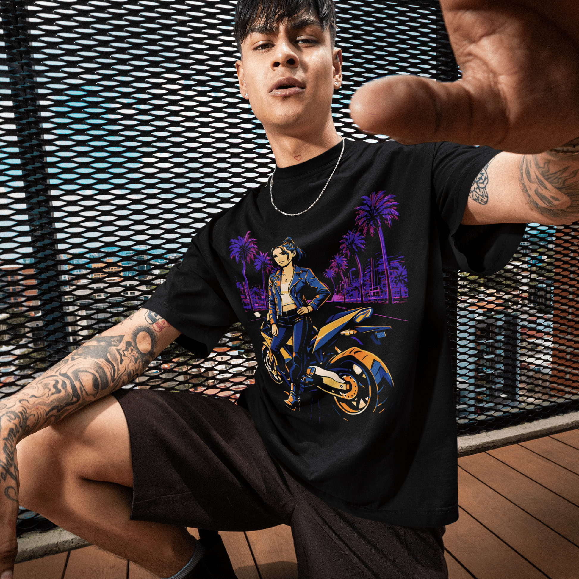 Person wearing a black t-shirt with a colorful graphic design, sitting outdoors on a wooden deck.