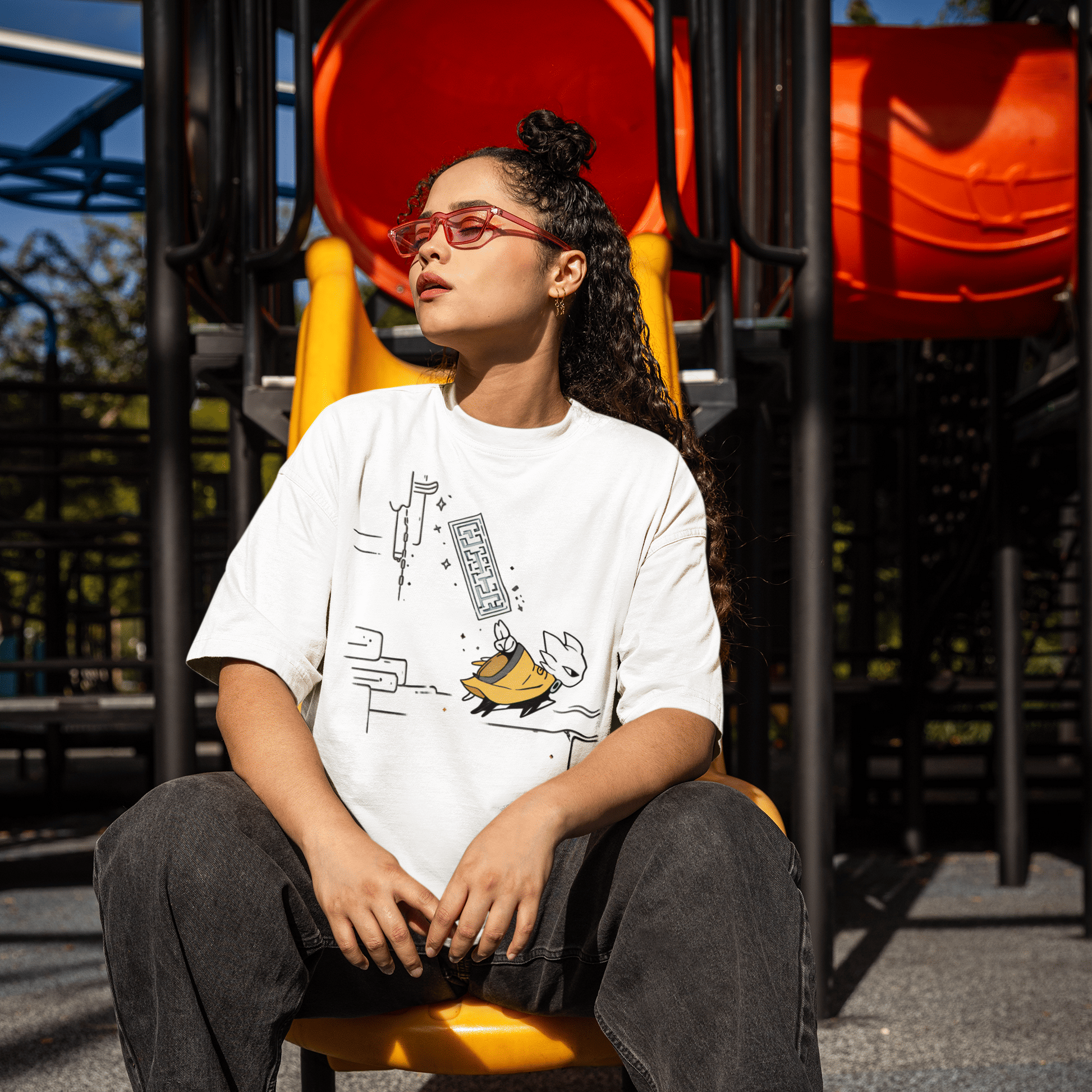 Male model seated outdoors wearing the white Nine Sols Action Tee – Seal Motion in a playground setting.