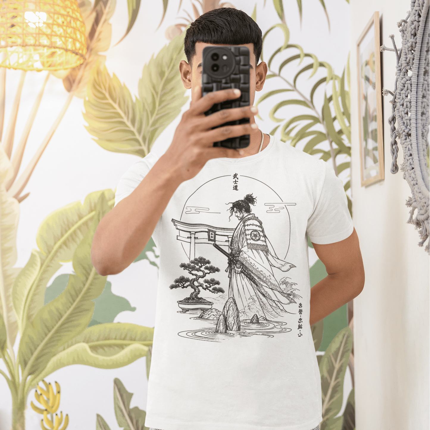 Male model taking a mirror selfie in Bushido Samurai T-Shirt with quiet warrior garden artwork in a bright tropical room.