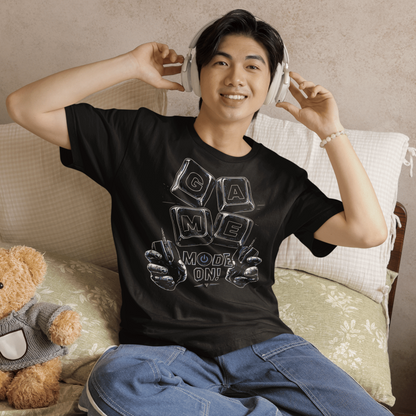 Smiling male gamer wearing Game Mode On T-Shirt with setup-inspired graphic during a cozy gaming night.