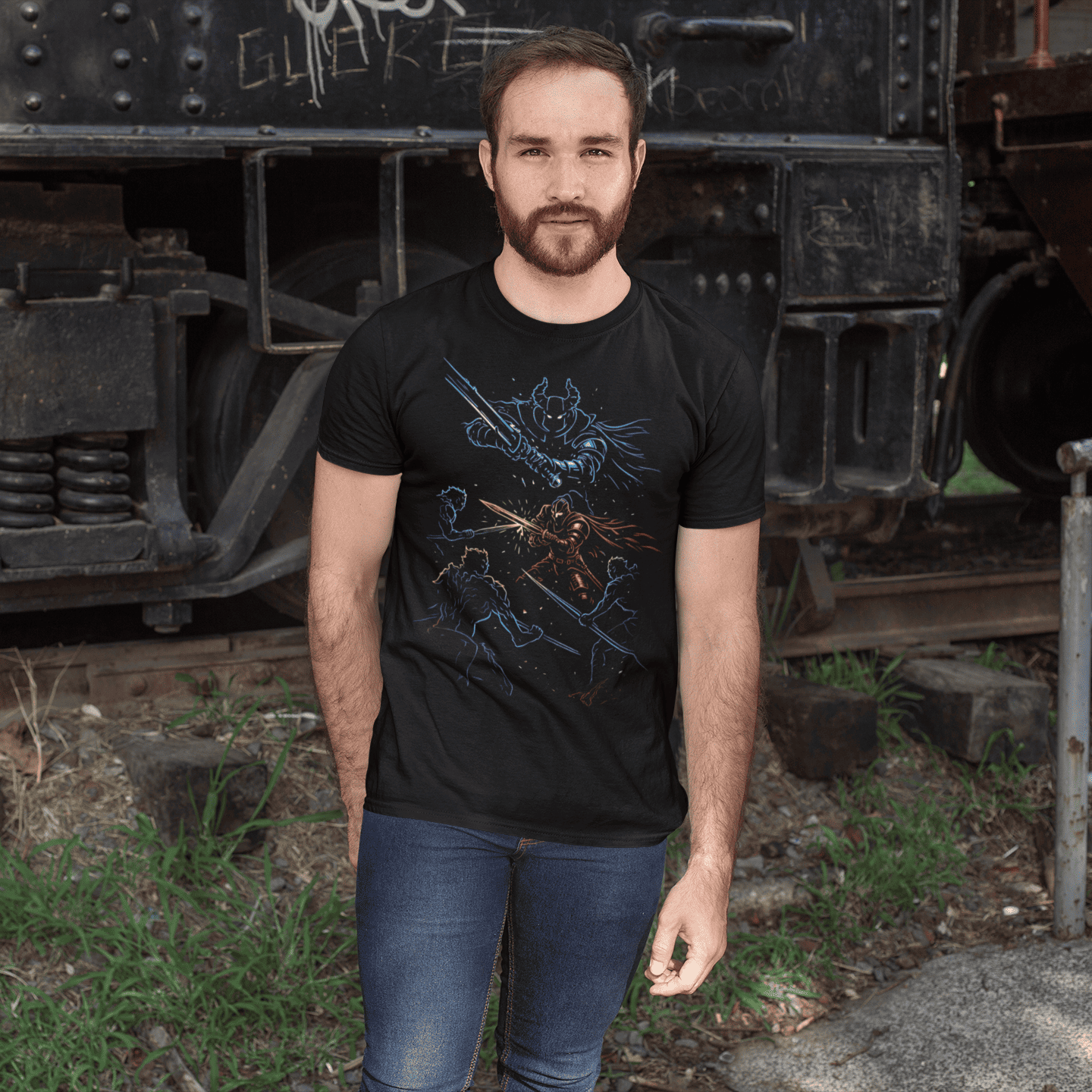 Man wearing a black t-shirt with a graphic design standing in front of an old train.