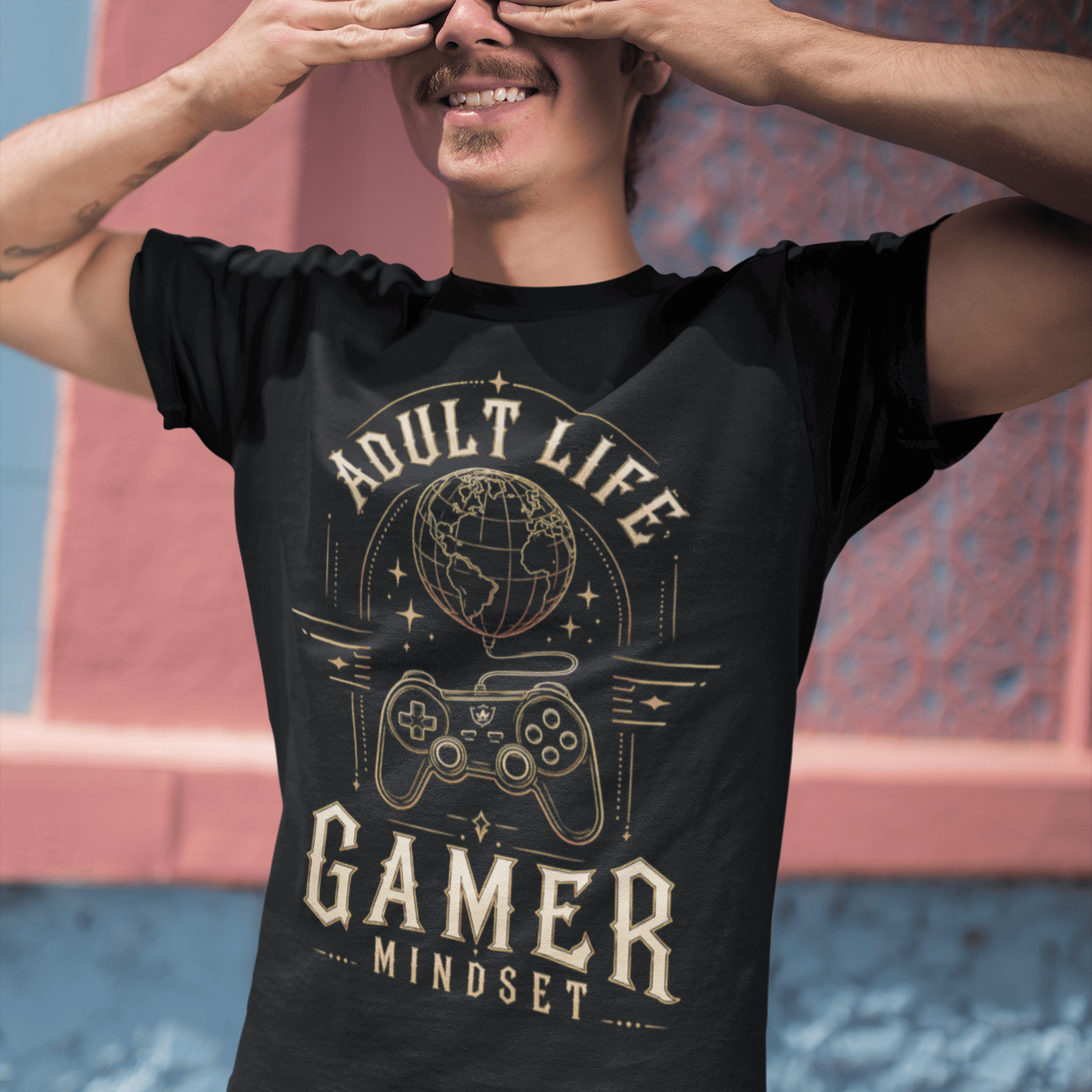 Male gamer covering his eyes in Adult Life Gamer Mindset T-Shirt with retro gaming graphic in an urban setting.