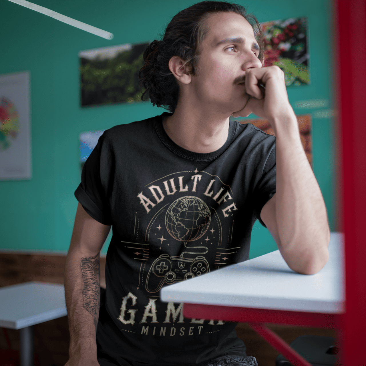 Male gamer leaning by a window in Adult Life Gamer Mindset T-Shirt with everyday gamer mode artwork.