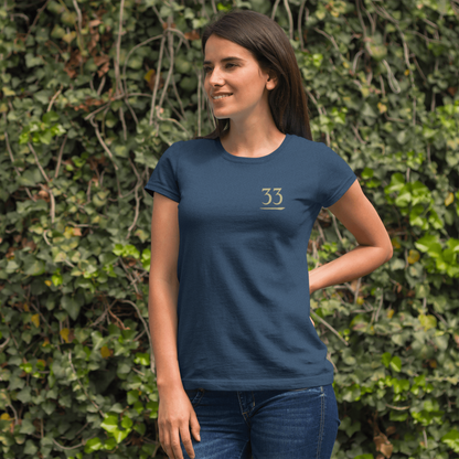 Woman wearing a blue t-shirt with a logo against a green ivy wall