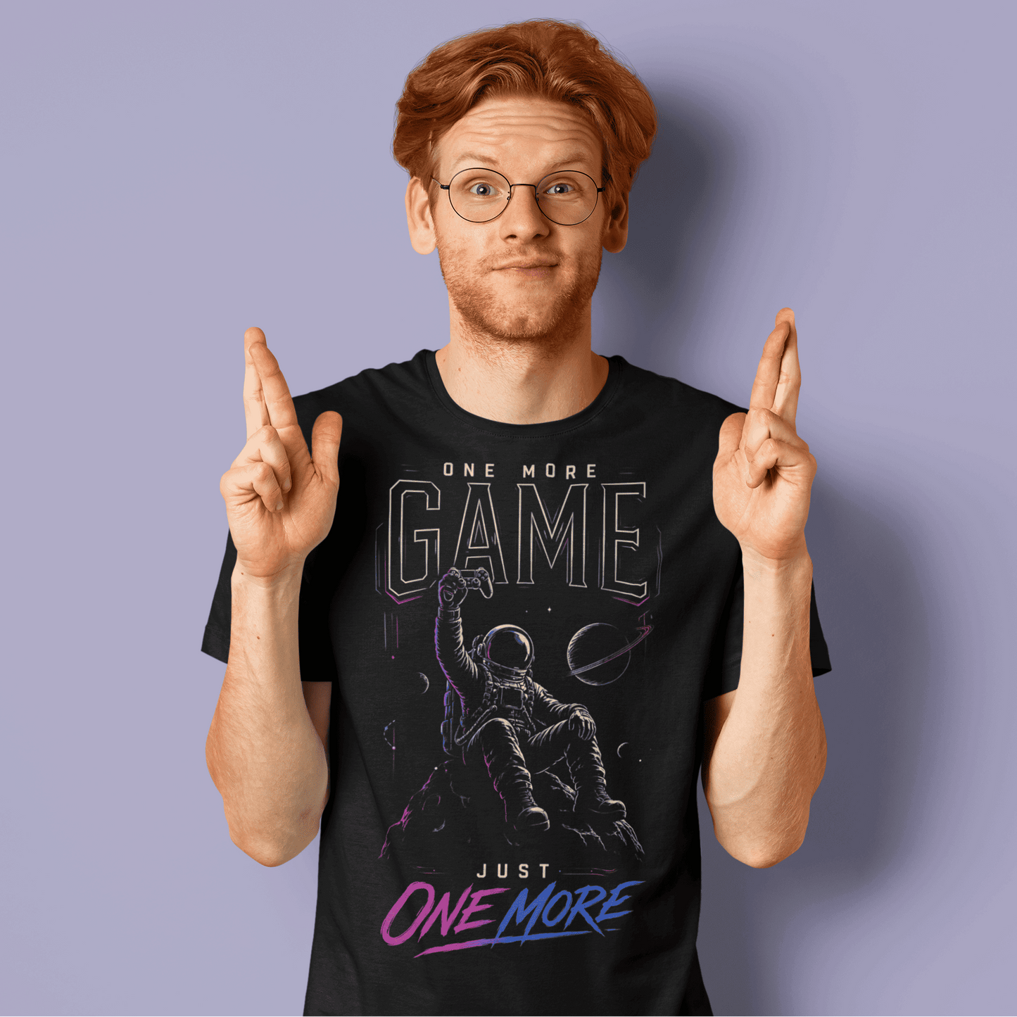 Male gamer crossing his fingers in One More Game T-shirt, a dark graphic tee inspired by late-night gaming sessions.