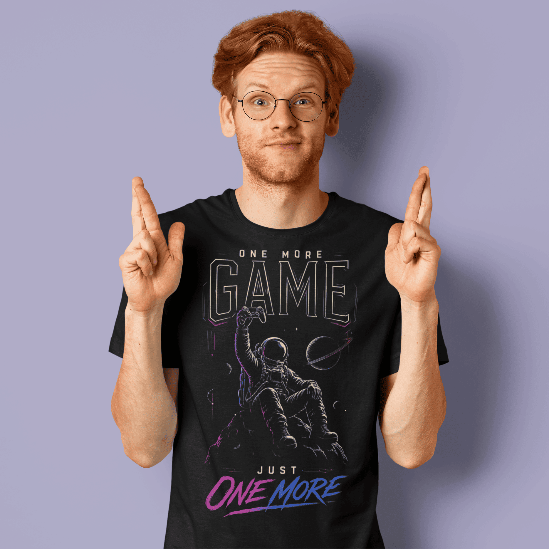 Male gamer crossing his fingers in One More Game T-shirt, a dark graphic tee inspired by late-night gaming sessions.