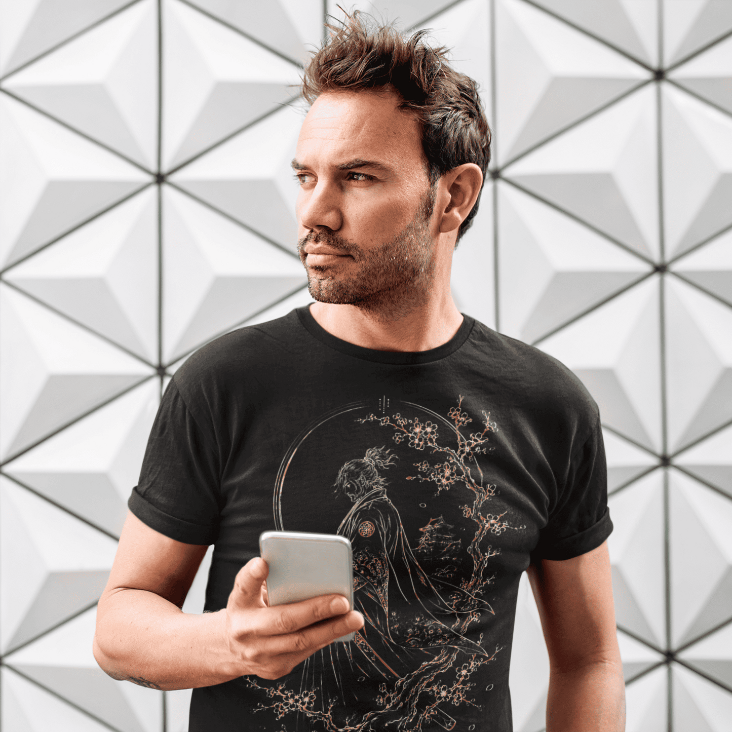 Male model holding a cup in Lone Samurai T-Shirt with warrior artwork against a white geometric wall.