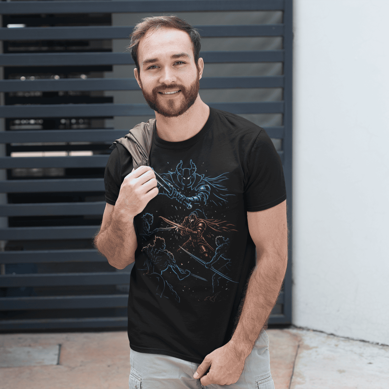 Man wearing a black t-shirt with a graphic design, standing in front of a modern architectural wall.