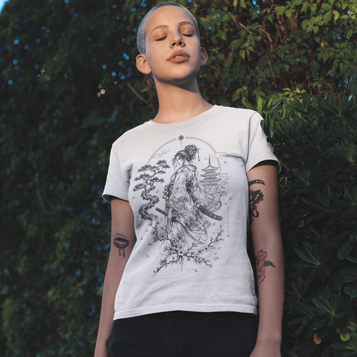 Female model in Kimono Samurai T-Shirt with detailed warrior artwork standing in a leafy outdoor setting.