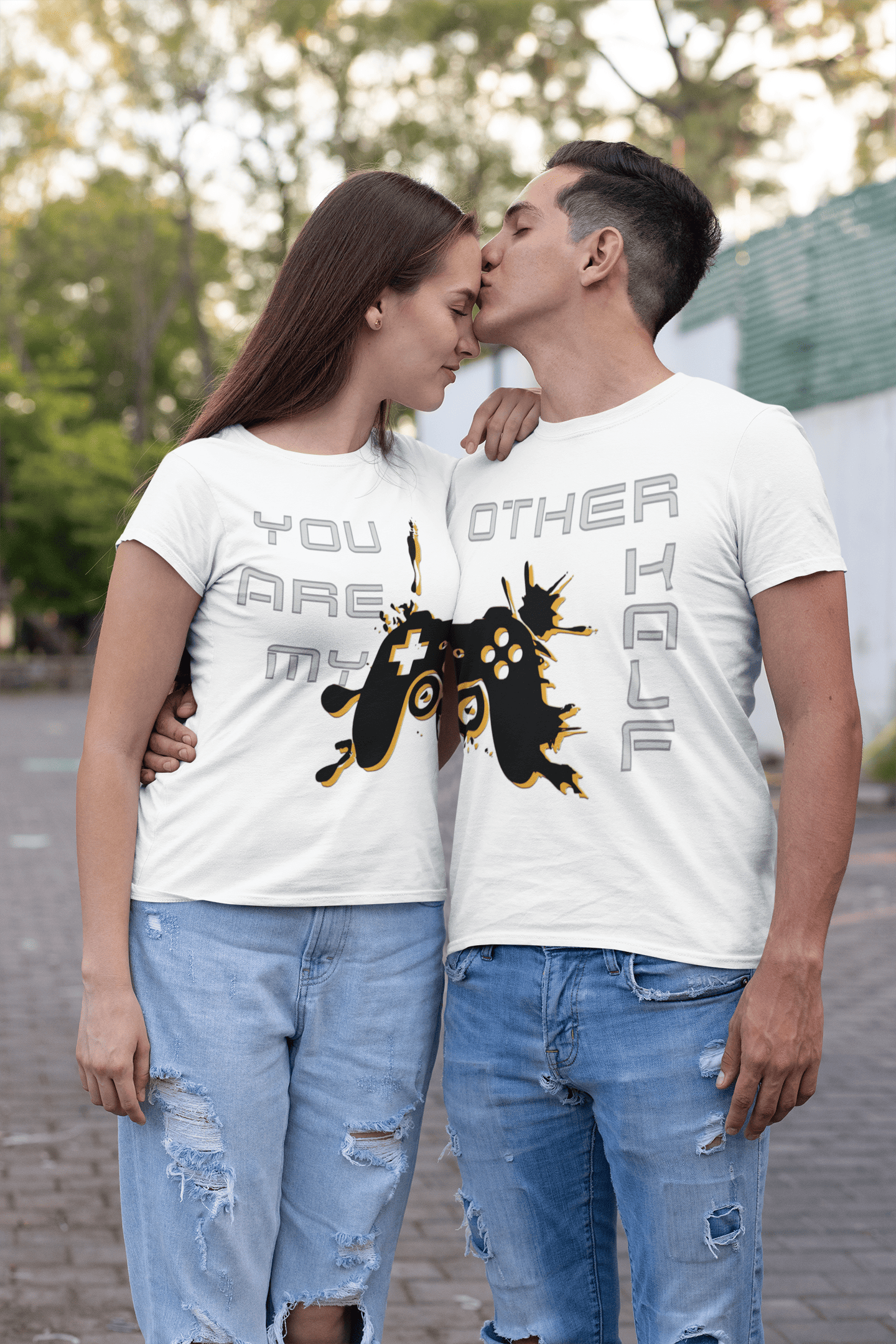 Couple wearing matching gamer t-shirts, man kissing his girlfriend outdoors