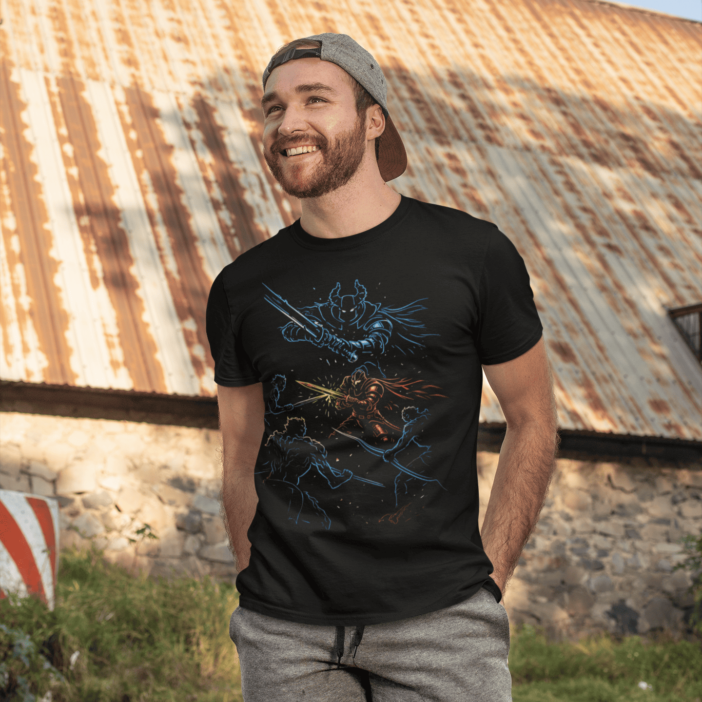 Man wearing a black t-shirt with a graphic design standing in front of a rustic building.