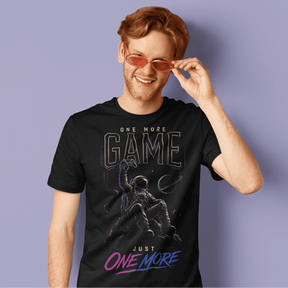 Male gamer adjusting his glasses in One More Game T-shirt, featuring a dark graphic inspired by one-more-game nights.