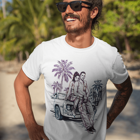 Man wearing a white t-shirt with a graphic design of a couple on a beach, standing on a beach with palm trees in the background.