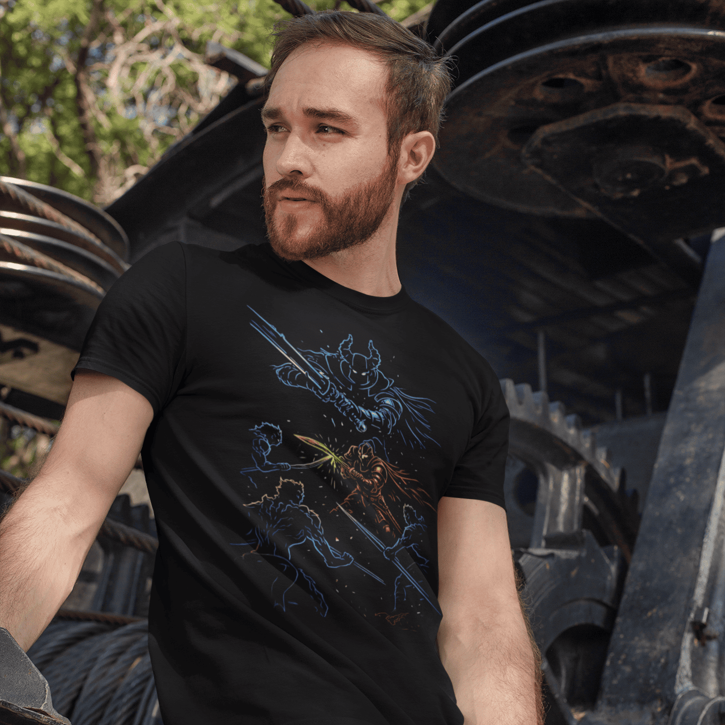 Man wearing a black t-shirt with a graphic design, sitting in front of large mechanical gears.
