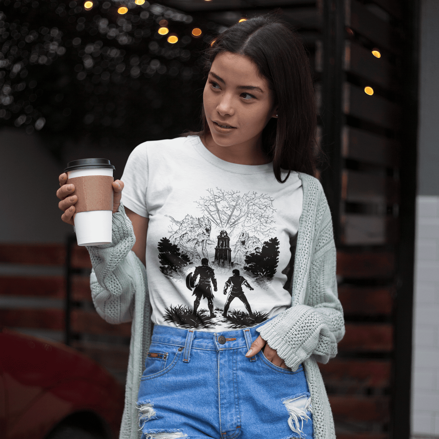 Woman wearing a graphic t-shirt with a coffee cup, standing outdoors.