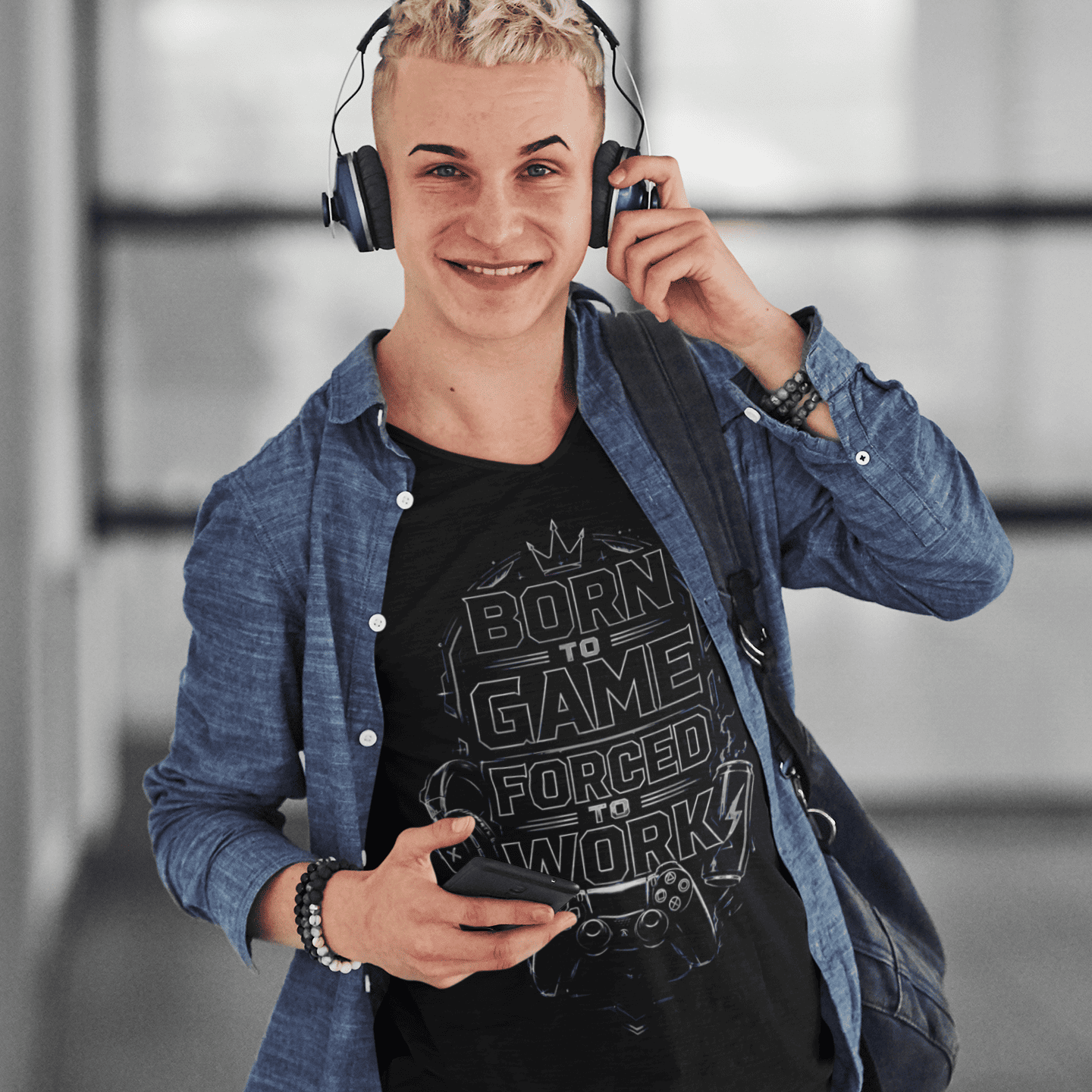 Front view of Born to Game Forced to Work T-Shirt – Headset Gamer Mode worn by a model adjusting headphones